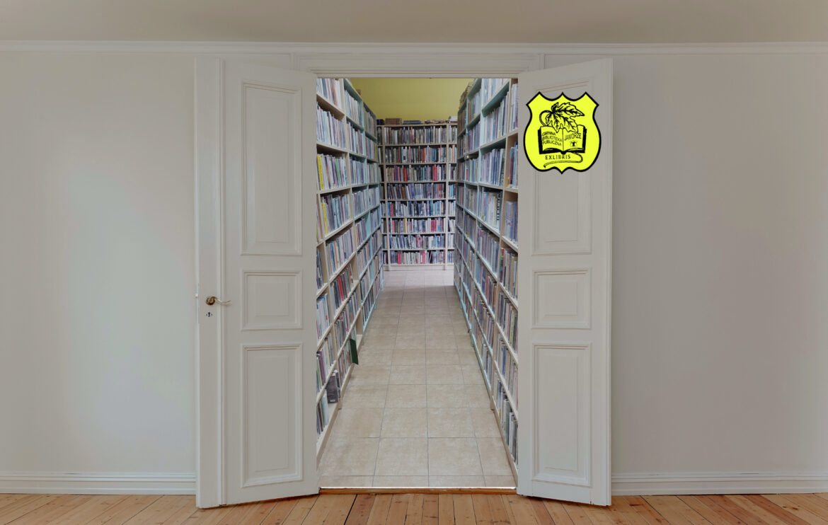 Otwarte drzwi wprowadzające do korytarza bibliotecznego, po prawej i lewej stronie na regałach rzędy książek